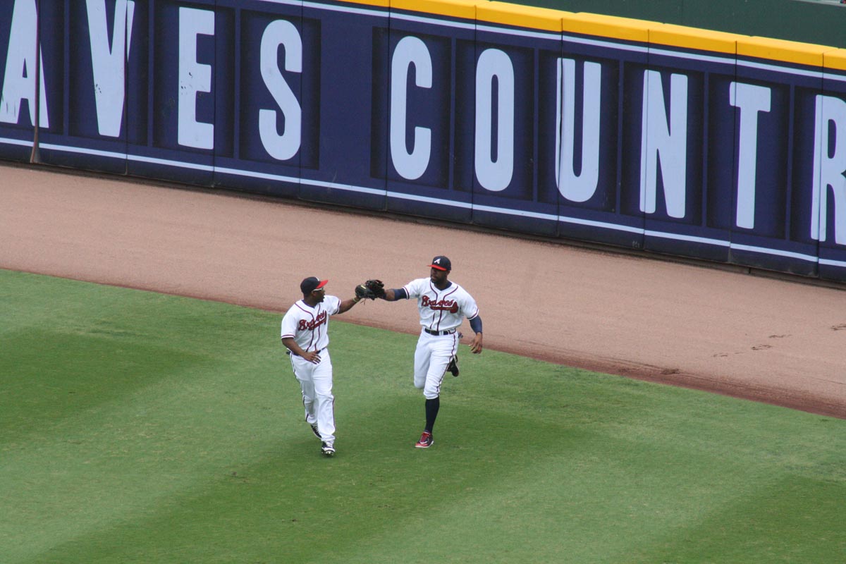 SOME LOVE FOR THE GLOVE: Michael Bourne and Jason Heyward celebrate after Heyward caught a warning-track fly ball to end the top of the first inning and prevent Colorado from scoring (caption by Luke Webster).