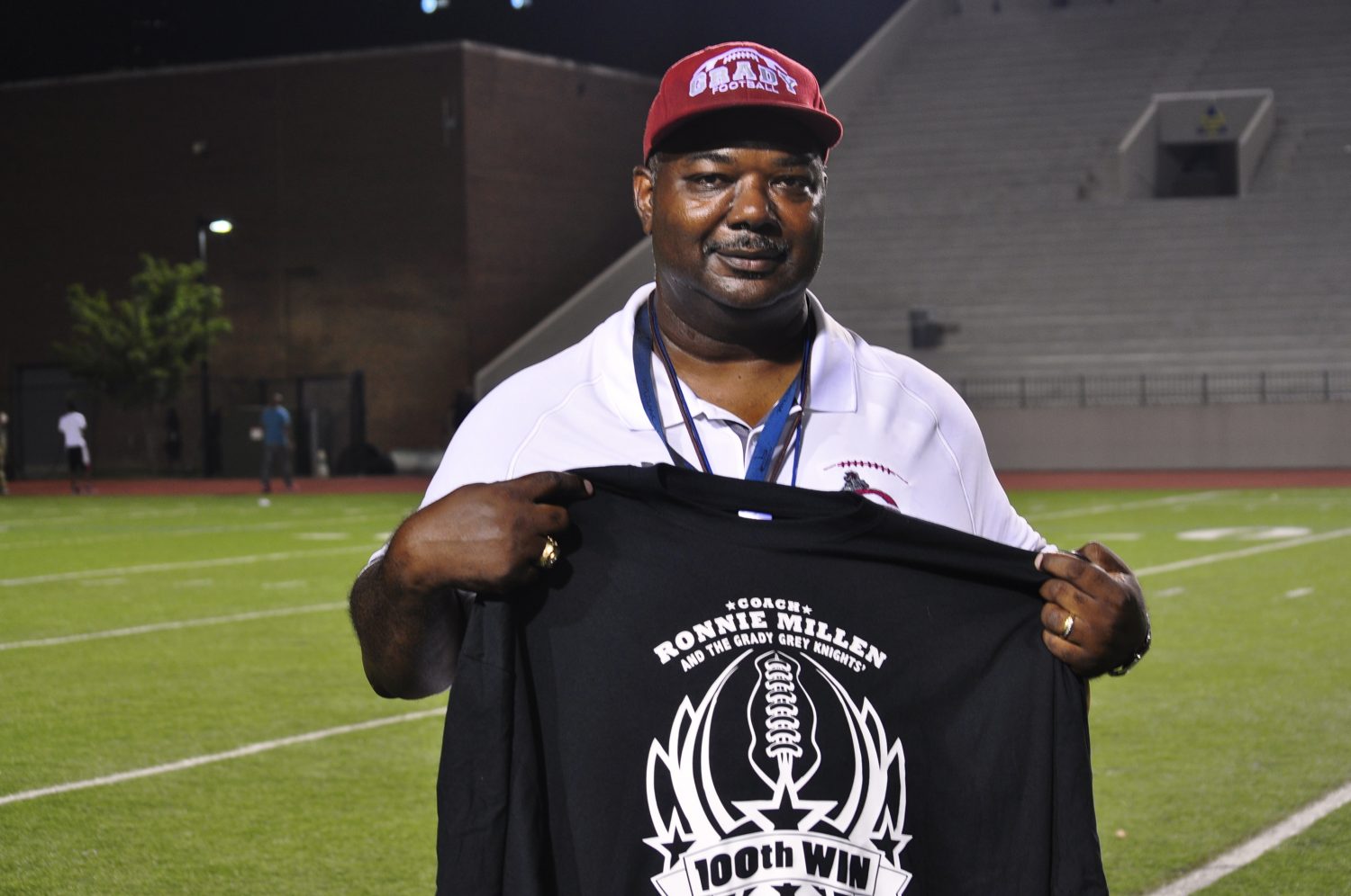 Coach Ronnie Millen poses with his 100th win t-shirt after the game. 