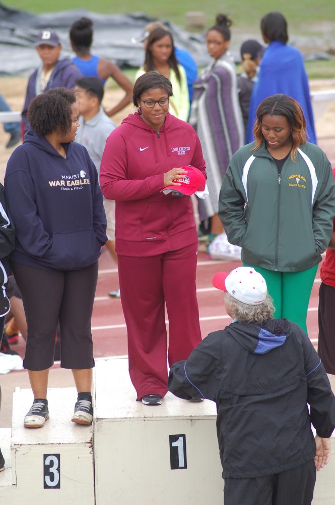 Woods stands atop the podium waiting to receive her second consecutive first-place award for the shot put competition in the state of Georgia.