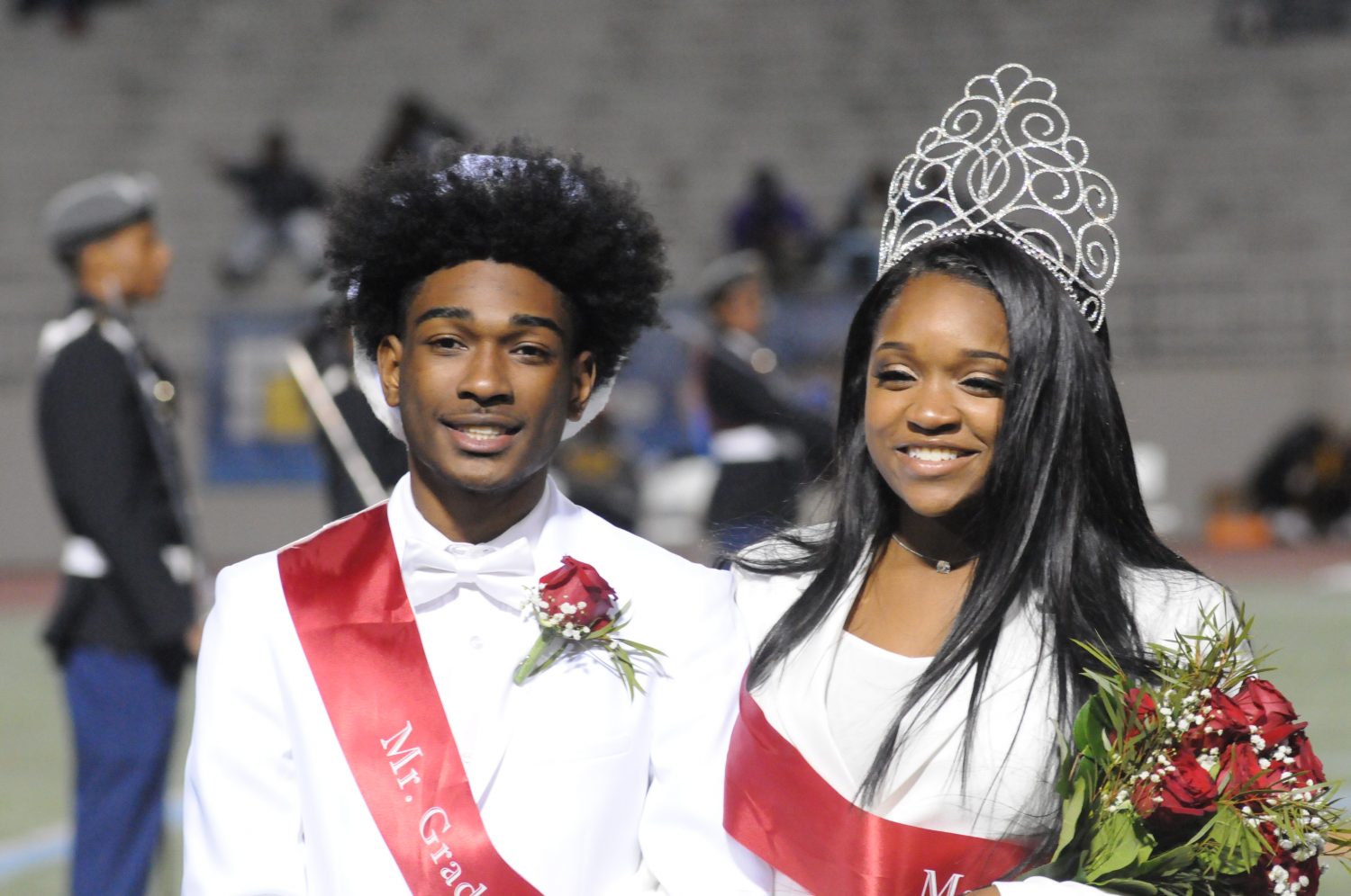 Ryan Young and Lauryn Bell, Mr. and Mrs. Grady, walk across the field during half time and wave to the crowd of students and families. 