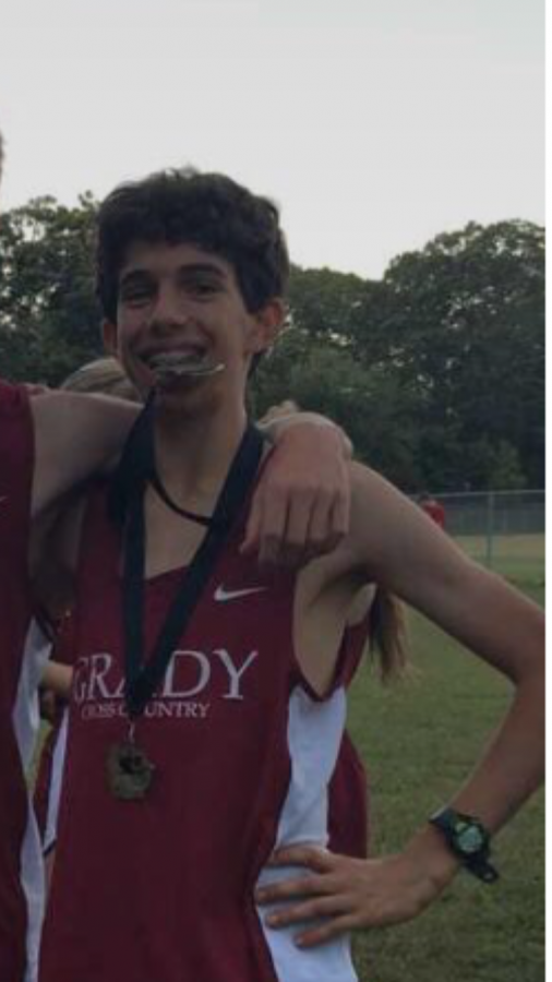 Jakes bites the gold after his team finishes first at the city cross country meet in 2017.