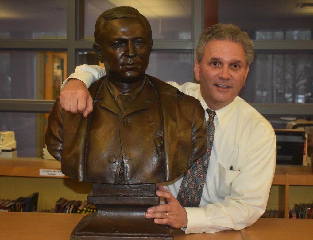 GENERATIONS OF GRADY: Henry Grady III stands with a bust of his great-great-grandfather, Henry W. Grady, after whom Grady High School is named. The bust is in the Grady library.