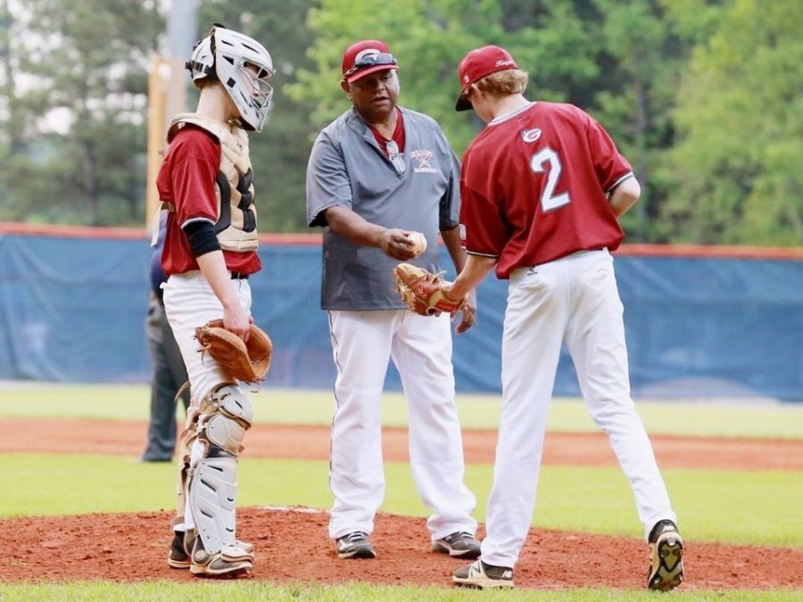 Coach Ron Killinsgsworth (center) confers with recently-graduated pitcher Luke Levens (right) and catcher Will McFarland (left) during a game in the 2017 baseball season.