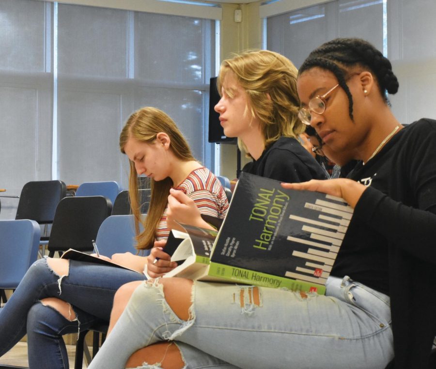 Senior Taylor Jackson, junior Gabby Nimmer and  senior Lucy Gelber look through their AP music theory books as Mr. Hill calls on students for answers.  