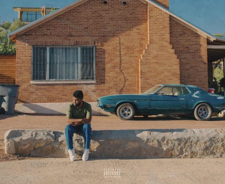 The+album+cover+depicts+Khalid+sitting+on+the+curb+of+a+yellow+brick+house+underneath+a+rich%2C+blue+sky%2C+showing+viewers+El+Paso+through+Khalids+eyes.