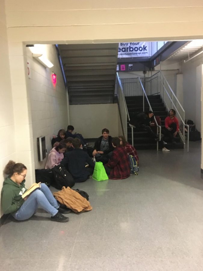 Students sit under the E Hall stairwell during the second lunch period. Not all students eat in the cafeteria. Many eat outside or use the time to prepare for class in the hallways, outside or the library.