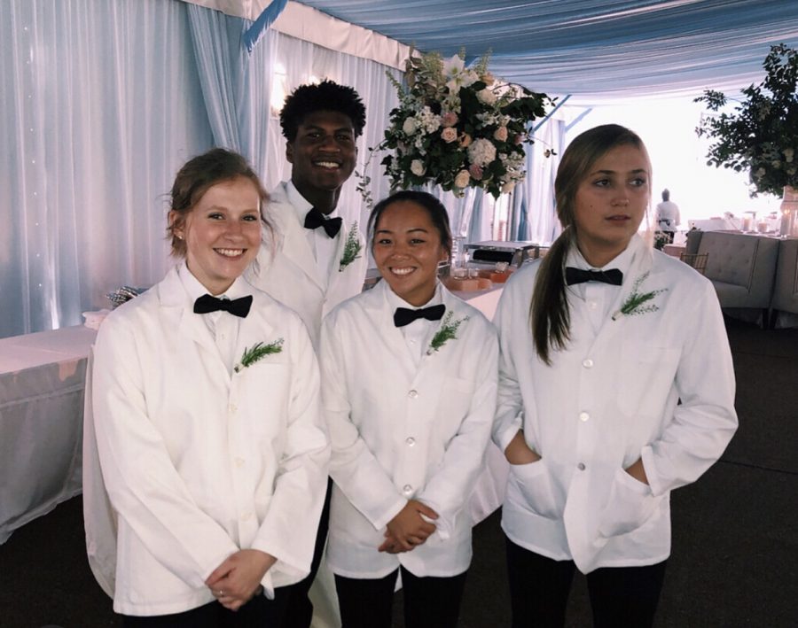 Alumni Melissa Drake, Camilla Kasper, and Georgia Smith (left to right) stand in front of senior Malachi Smith after setting up food for a wedding.