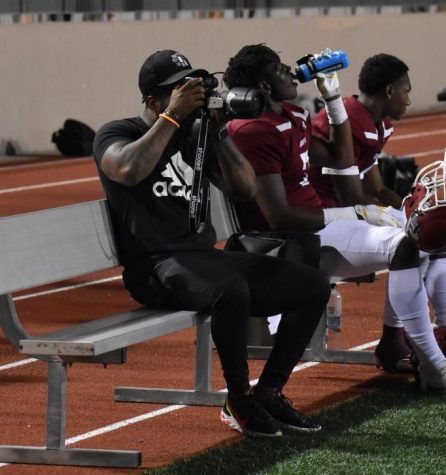 Former Grady quarterback Simeon Kelley (left) focuses the camera on the action from the bench as senior tight end Dewan Wright (center) squeezes a swig of water and current quarterback and senior Aquinas Stillwell (right) takes a breather. Kelley, now a photographer for Atlanta Public Schools, led the Knights to an undefeated regular season and state semifinals finish in 2005.