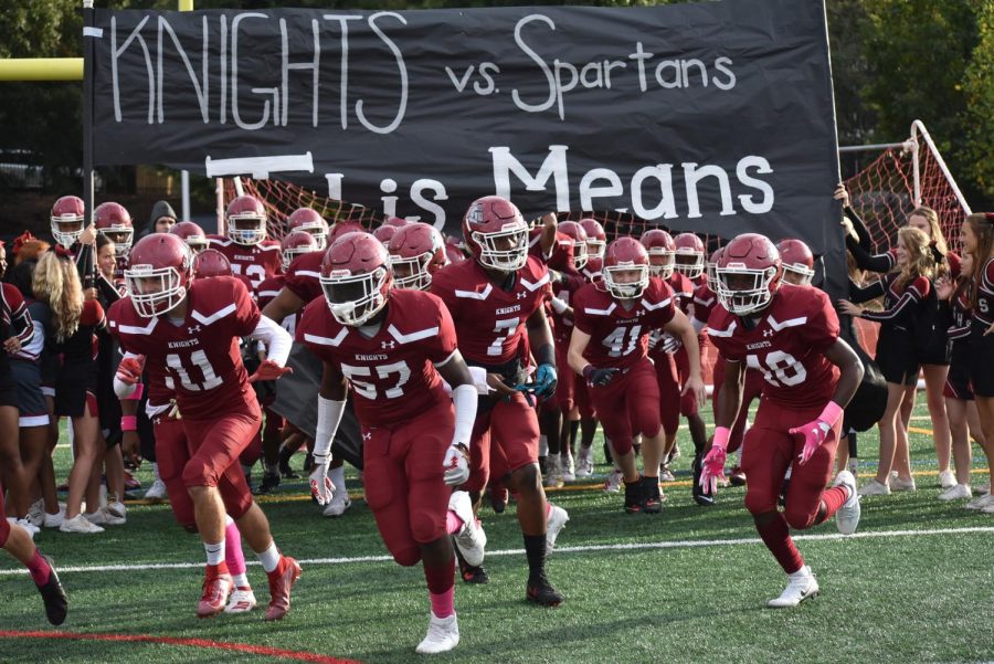 The varsity football team bursts through the banner prior to the start of the homecoming game against North Springs on Oct. 18. The Knights won 40-0.