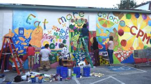Grady Cluster teachers and students paint community mural on the wall of the Candler Park Market.