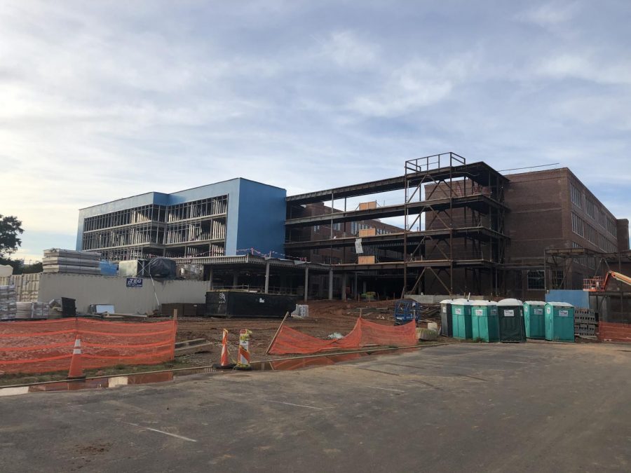 The photo displays the David T. Howard building under construction as of October 2019. The new addition to the structure is shown on the left hand side of the photo. It is a blue material lined with a metal frame. The remains of the original school can be seen on the right of the photo. The freshly laid concrete is also visible in the foreground.