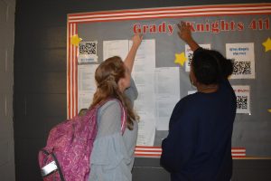 Vice President Nora Ball (left) and President Alaya Foote (right) of SkillsUSA plan the new bulletin board the club will be in charge of. The board located outside the library will display school news directed to inform students. 