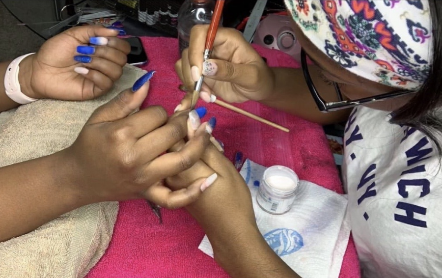 Zhariah Mitchell applies acrylic to her clients nails. The acrylic is placed on top of the nail extensions to give the nails a longer and fuller look.