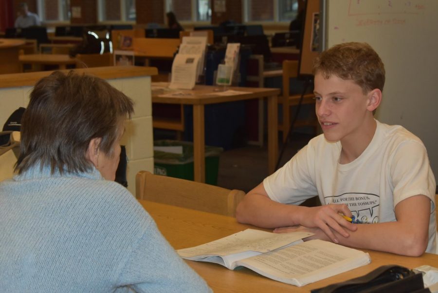 Freshman Sam Prausnitz-Weinbaum seeks help on an AP Human Geograpy assignment from former journalism teacher Riki Bolster at the writing center. The center is open Mondays and Wednesdays after school and Tuesdays and Thursdays by appointment.