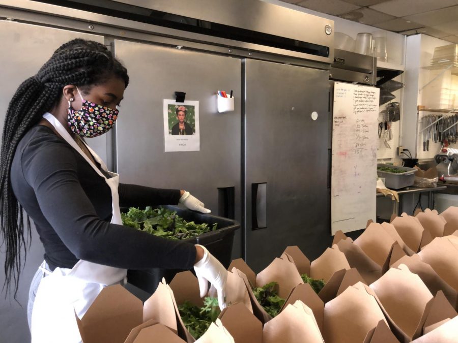 Avalon Caterings Pastry Chef, Sitara Ward, fills up boxes with mixed greens which are to be sent out to health care workers.