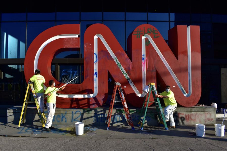 Workers scrub off graffiti from the CNN sign.