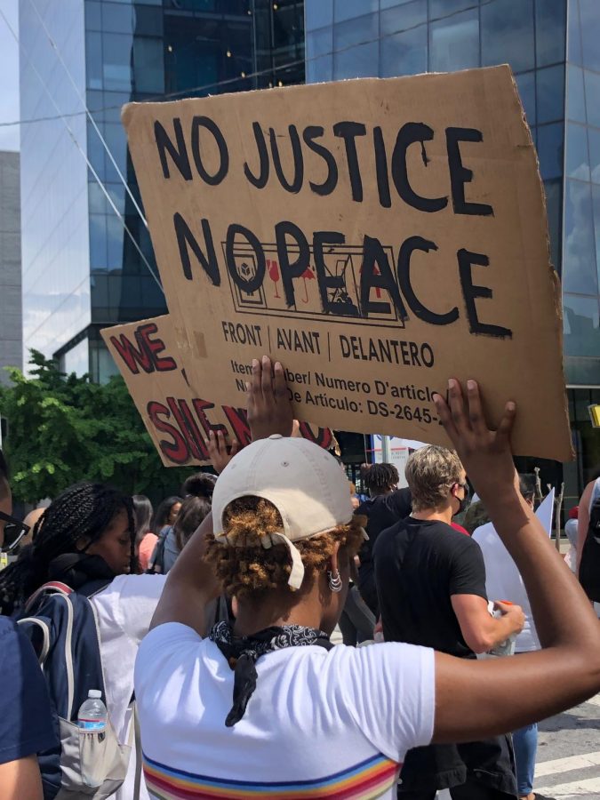 A participant of the March 29 protest against police brutality holds a sign saying "No Justice, No Peace."