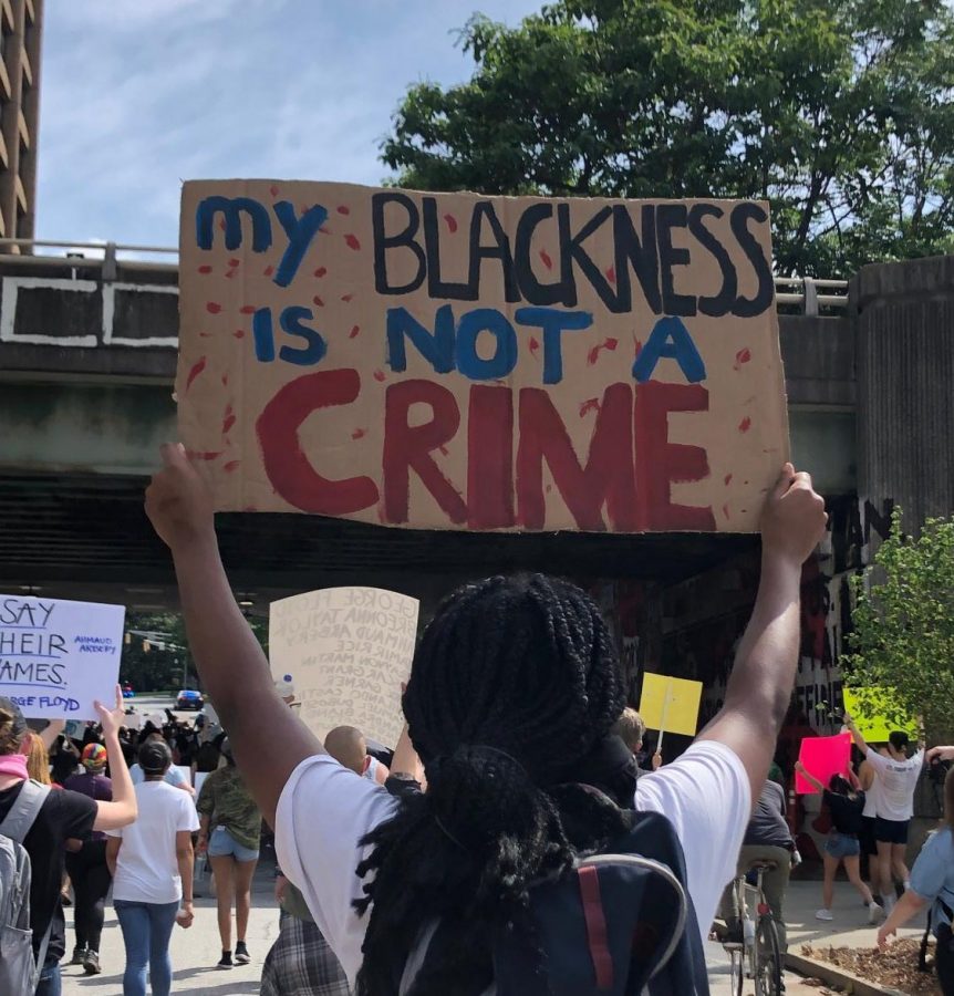 A protester at the Justice For Us march on May 29 holds a sign reading "My Blackness is Not a Crime."