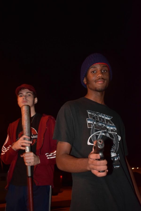 Director Jack DiCarlo, senior, and actor Langston Hogan, junior, hold a bat and a prop gun used in the film.