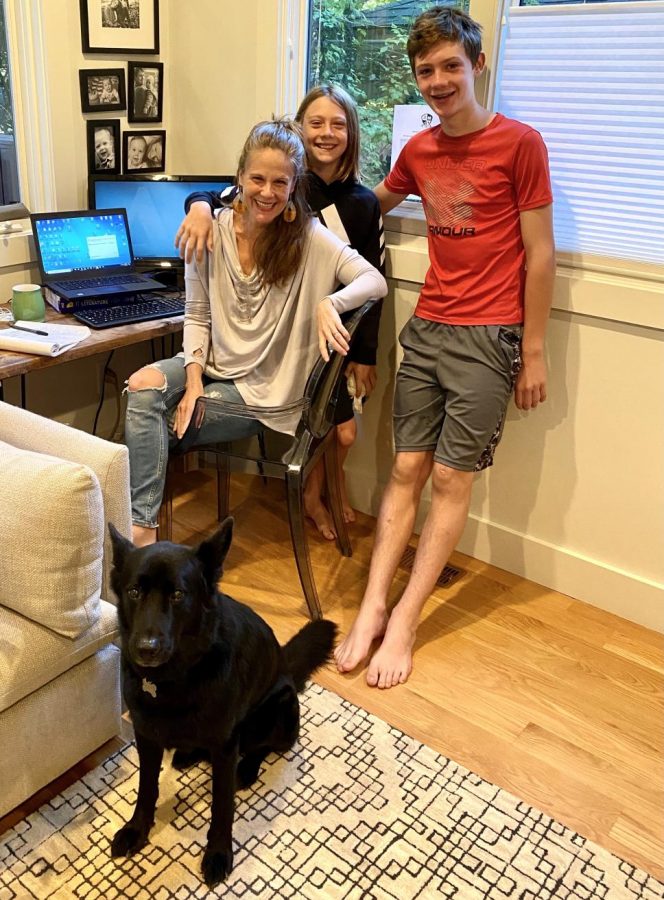 Carter and her kids pose in front of her work space set up with their dog.