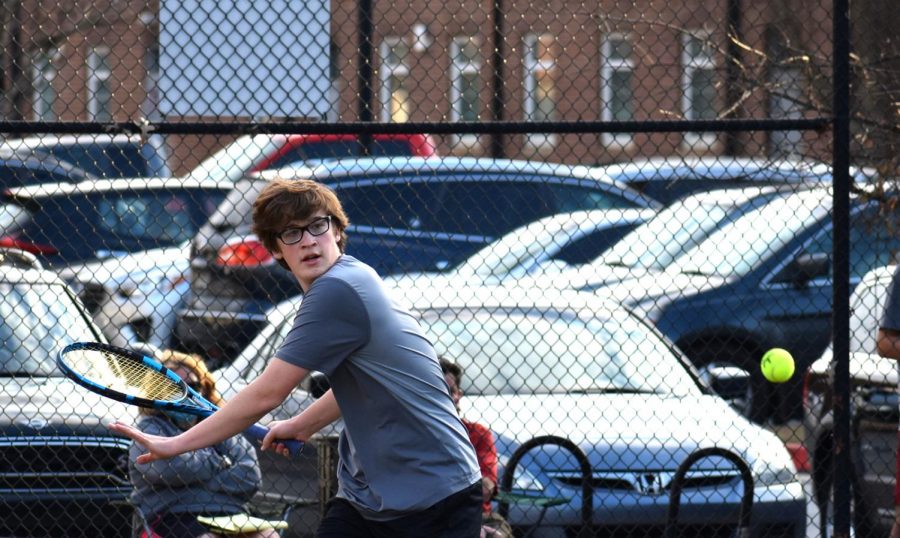Junior George Smalley returns a volley in a doubles match against St. Pius on Feb. 10. Boys tennis beat St. Pius 2-1, while the girls lost 3-0