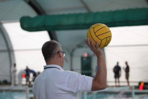 A water polo referee holds a ball during timeout.