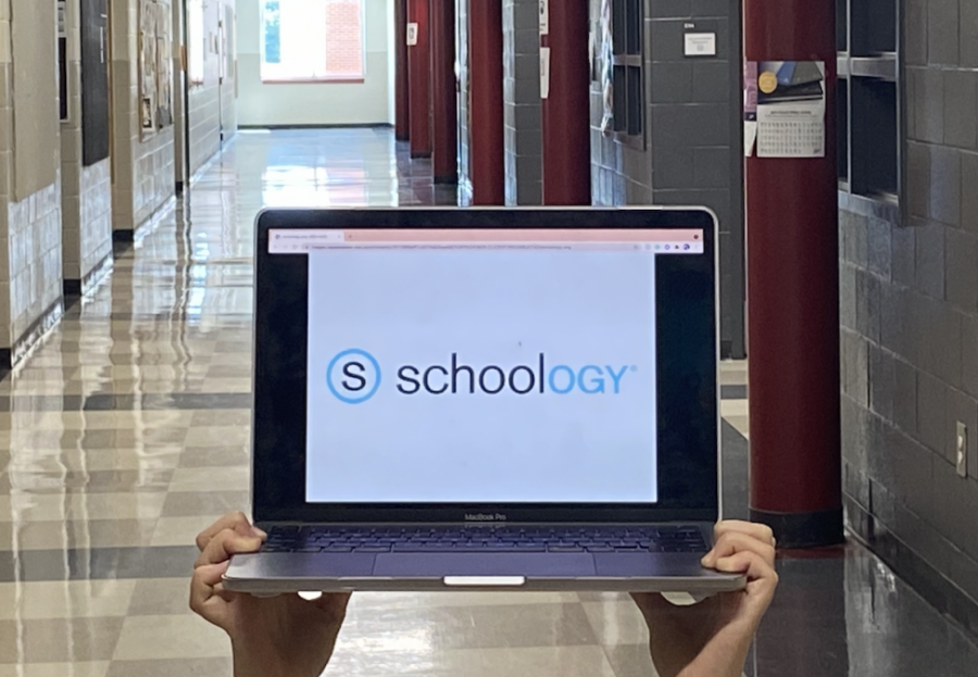 A student holds up a computer with the Schoology logo on it in a hallway at Midtown. Schoology, a learning management software, has been recently implemented at Midtown. 