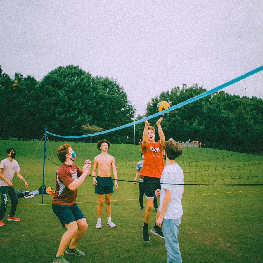 Tate Smith bumps the ball back across the net while senior Lucas Damiani waits on the other side of the net to return the ball at a meeting for volleyball club in Piedmont Park.