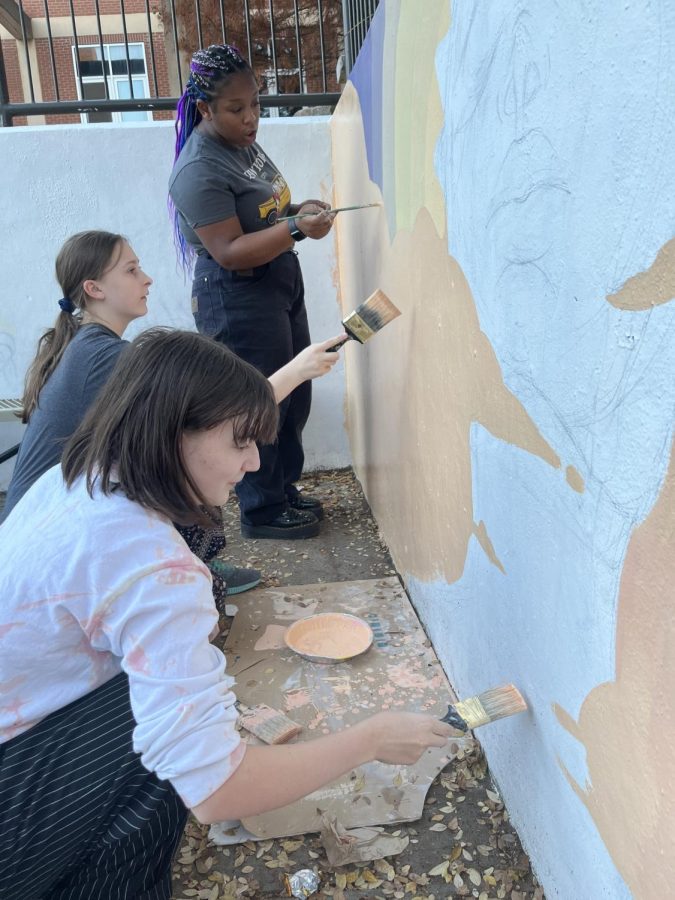 Freshmen Piper Boatright, Dani Kote and Ivy May continue working on Boatrights courtyard mural. The mural will consist of a sun goddess rising through the clouds.