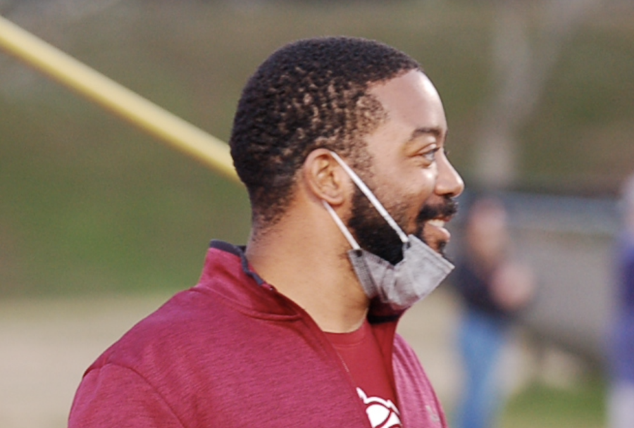 Girls track head coach Josh Washington laughs with an athlete at the 2022 Midtown Opener. Washington credits his success as coach to the relationships hes built with his athletes.