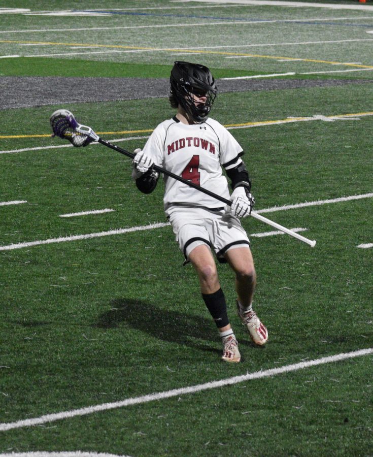 Junior midfielder Brian Edwards cradles the ball and looks for a pass during the boys lacrosse teams season opener against East Cobb. The Knights lost 6-4, Edwards scored two of the Knights four goals.