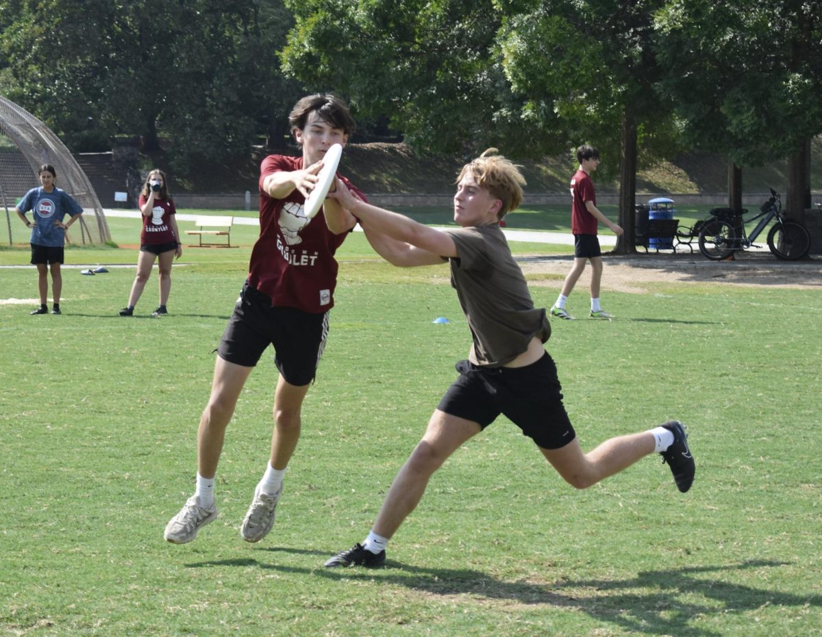 Junior varsity ultimate player Grady Richman competes with sophomore Callan Meyer to catch a disk mid-air at one of the team's captains practices that allow the team to warm up before the official season.