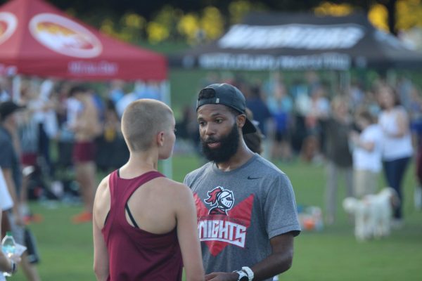 New assistant cross country coach Jamal Willis gives encouragement to sophomore James Roberts before the APS Cross Country Championship on Oct. 1, where the Knights placed third.