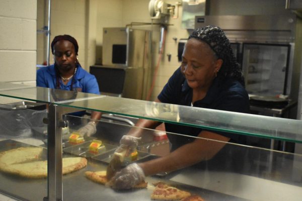 SERVING UP: Midtown lunch staff, Vema Storymolden, cuts pizza for students. This year, Atlanta Public Schools has increased accessibility for students involved in the Community Eligibilty Provision, which provides free meals to students. 