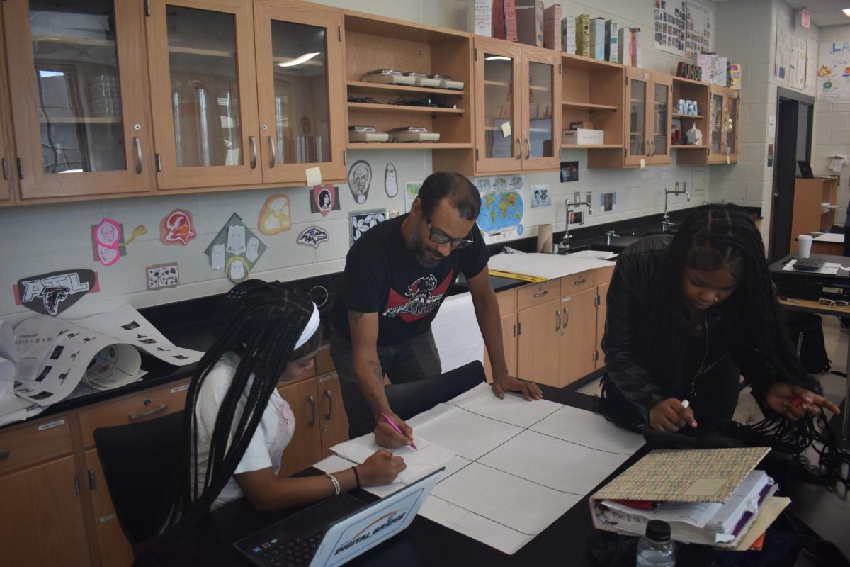 AN ESSENTIAL COMPONENT: Science teacher Dominico Kantor helps students in chemistry class. The quality of secondary education in Atlanta has contributed to the designation as first city in education by Forbes.