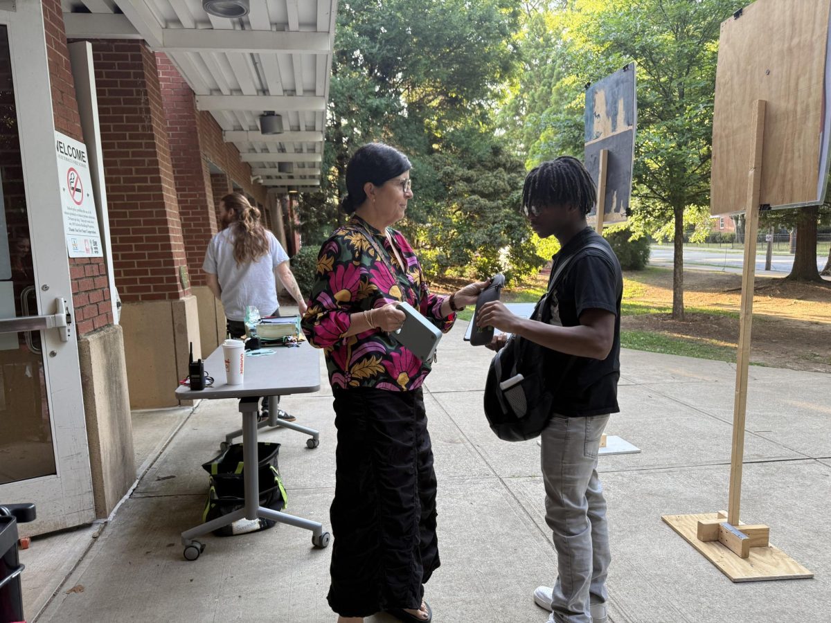PUTTING IT AWAY: Student Support Specialist Dr. Cheryl Nahmias unlocks a student's Yondr pouch. 2024-25 was Midtown's first year using this system. 