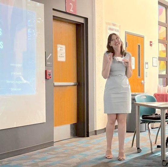“The Unmasking” advisor Erin Aube introduces the magazine at Midtown's first Journalism and Communication Booster Club meeting.