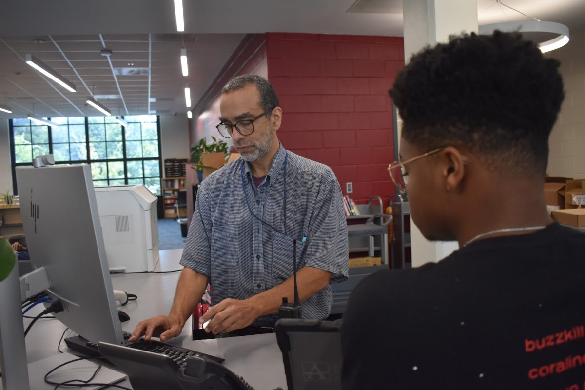 COMMUNITY CENTER: Midtown media specialist Brian Montero helps a student in the library. Montero said students come to the library for studying, projects, reading and to decompress.