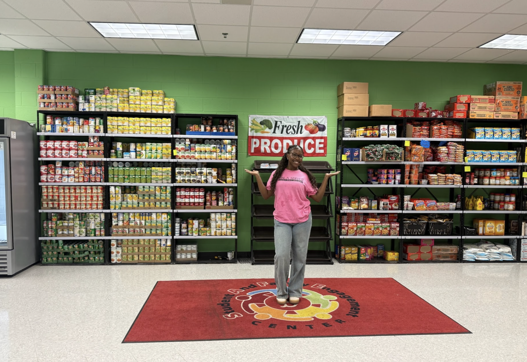 Senior Star Winborn poses under Fresh Produce sign at Banneker High School food pantry. Winborn organizes food distribution for the S.A.F.E. Center as an ambassador and a member of Young Black Leaders of America ( YBLA).
