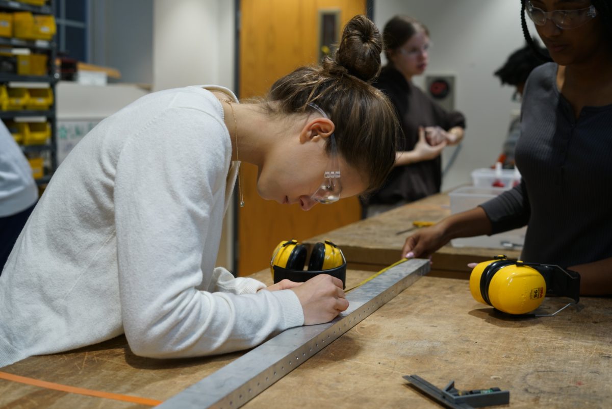 Freshman Emma Striedinger (left) and junior Leila Yalew (right), assembly leads, measure metal in the shop.