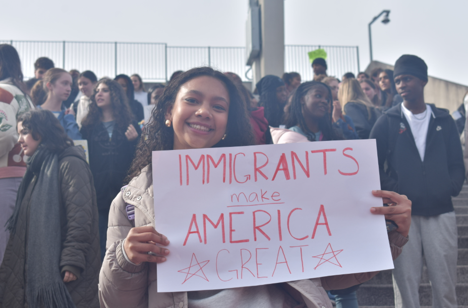 HELPING HAND: Senior Maya Gordon hold up handmade poster at Midtown's anti-ICE walkout on Jan. 29. Students left their 3A and 4A classes and listened to student speakers in Henderson Stadium.