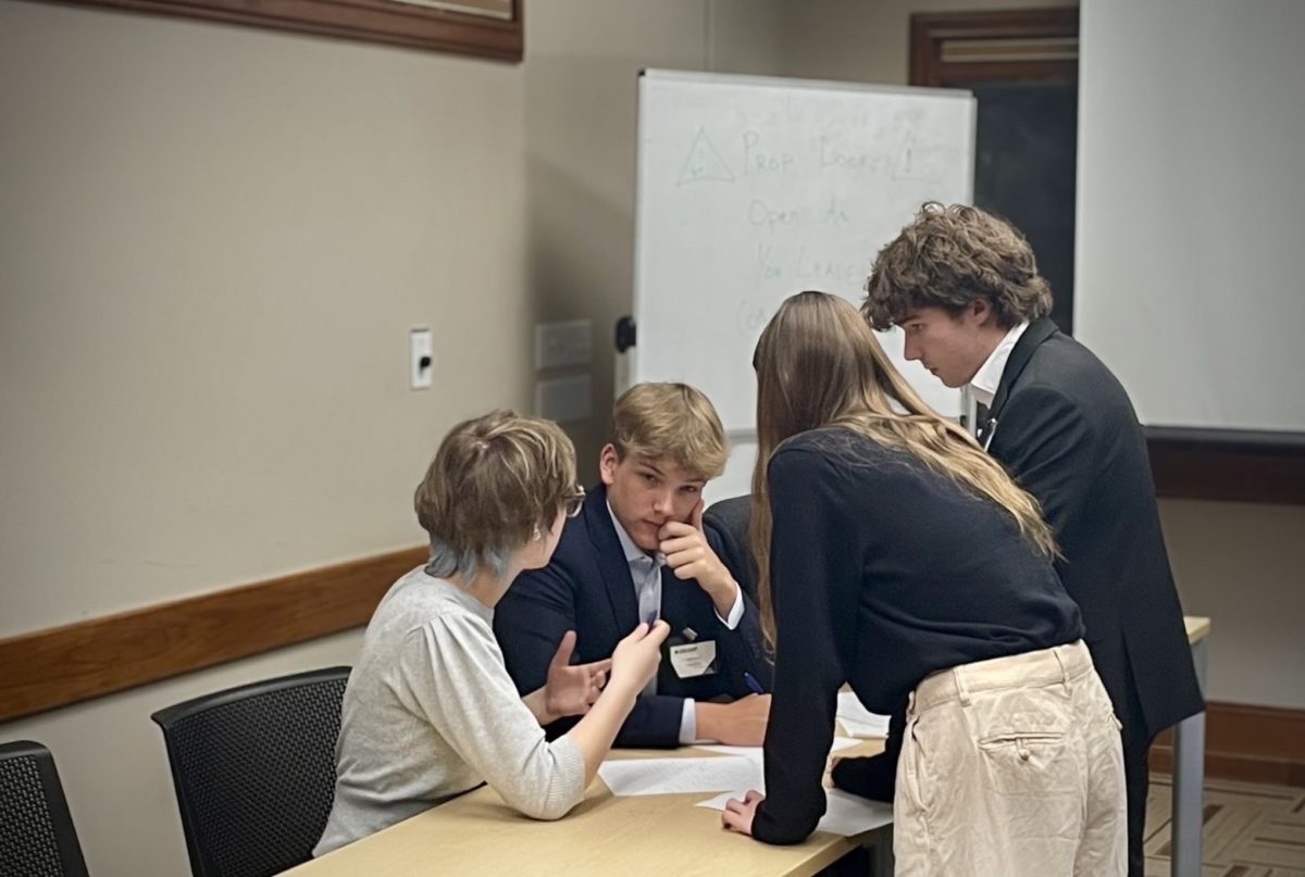 STRATEGY IN SESSION: Juniors Georgianna Madge, Colin Kovac and Liam Valentine huddle with freshman Anna Ward during Midtown's preliminary-round match at the National High School Ethics Bowl Championship on April 11 at Duke University.